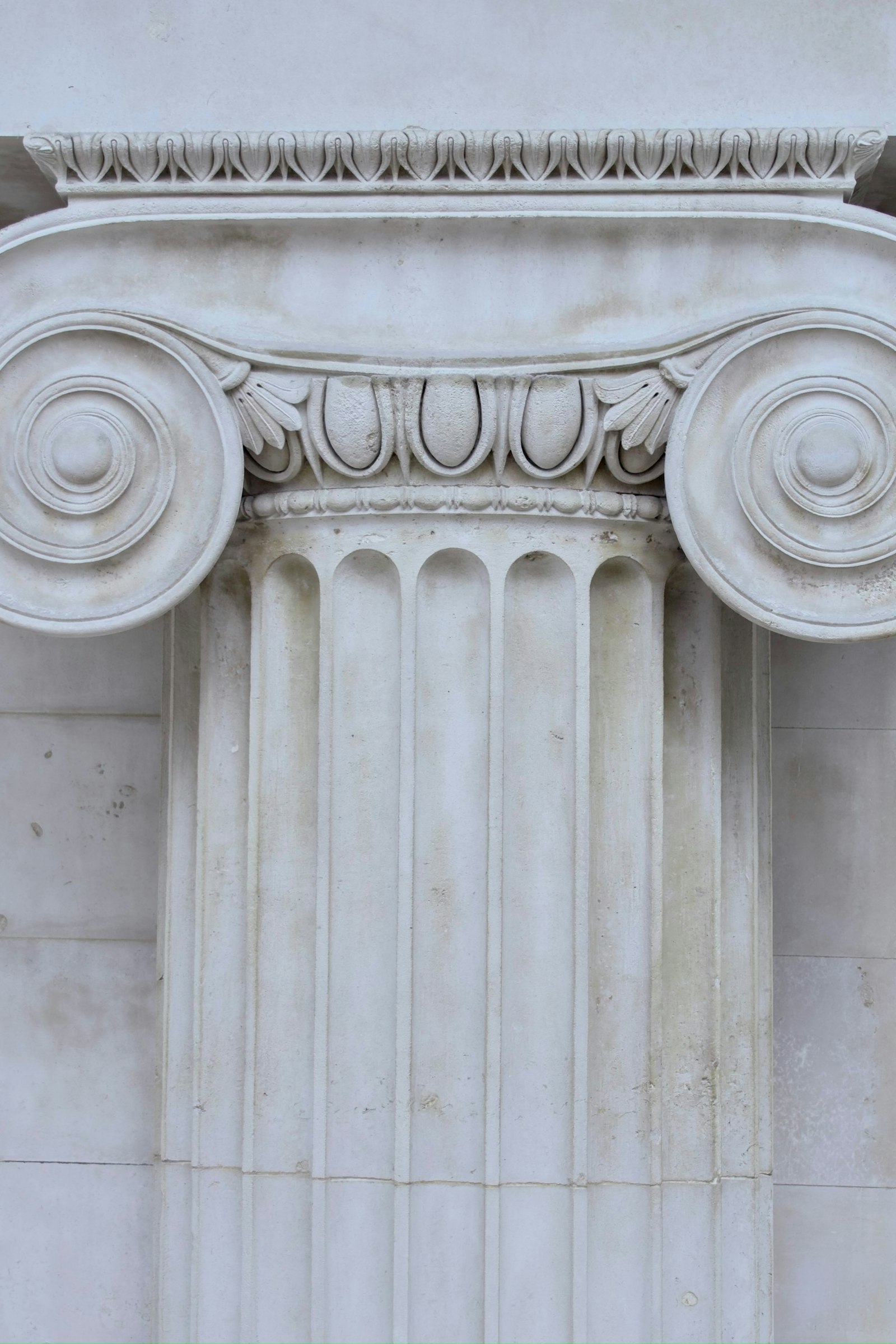 Close-up of a classical stone column capital, representing the stability and permanence of fixed income investing.