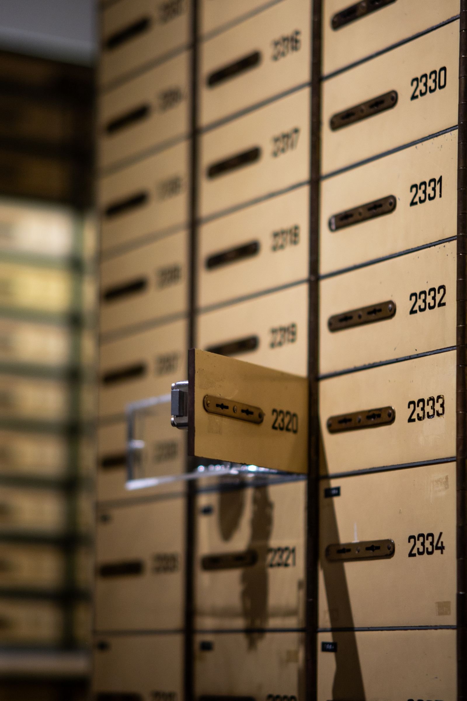 A wall of numbered safe deposit boxes with one box door open, representing the structured, scheduled access windows of a flex deposit.