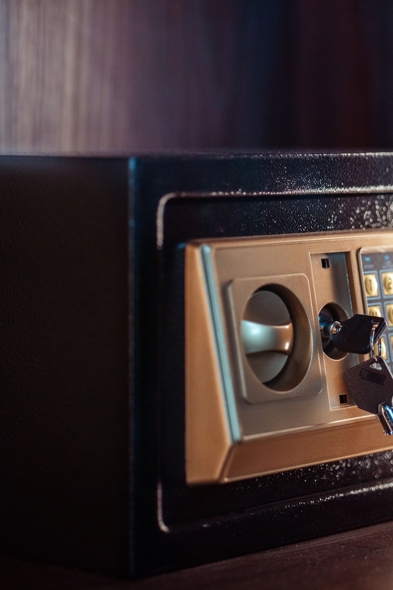 Close-up of a black home safe with a gold keypad and key inserted in the lock, representing the security of a savings account.